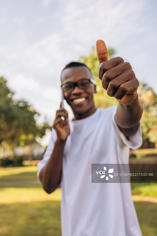 户外微笑的男人一边打电话一边竖起大拇指图片素材