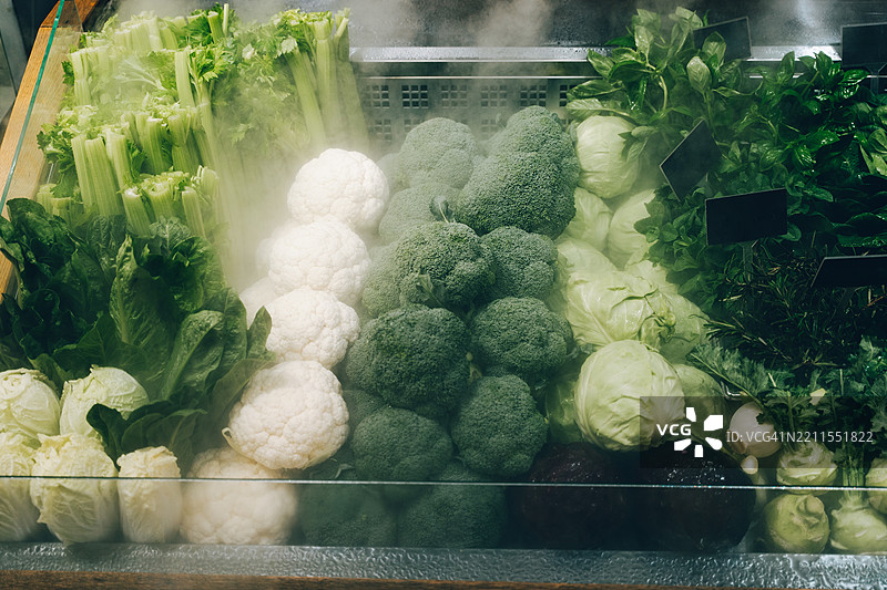 新鲜绿色蔬菜在冷藏展示柜中蒸汽腾腾图片素材