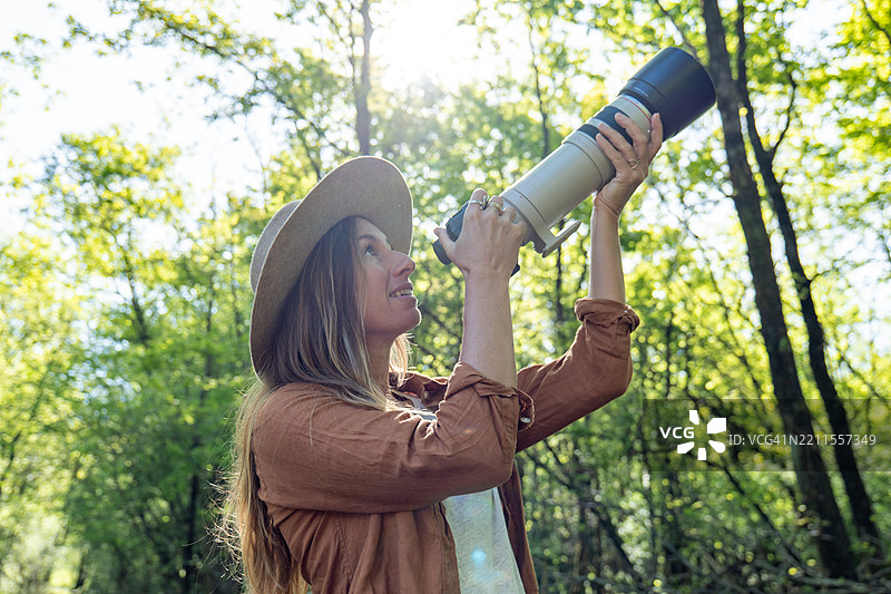 女性在森林中用大镜头观察自然图片素材