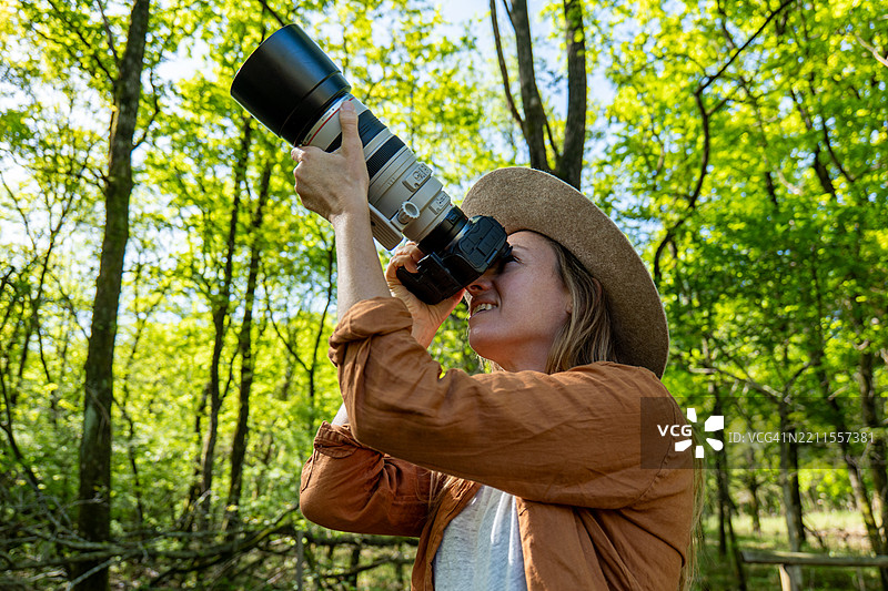 在森林中用大镜头观察自然的女性图片素材
