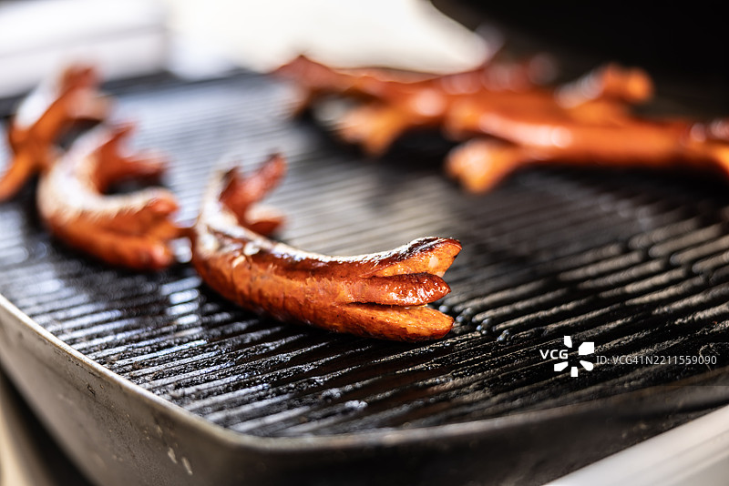 美味多汁的胡椒香肠在花园烧烤架上烤制。图片素材