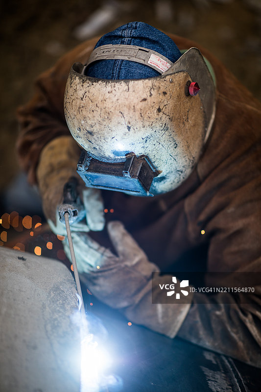 穿着防护装备的焊工正在进行电弧焊接，四周飞溅着火花图片素材