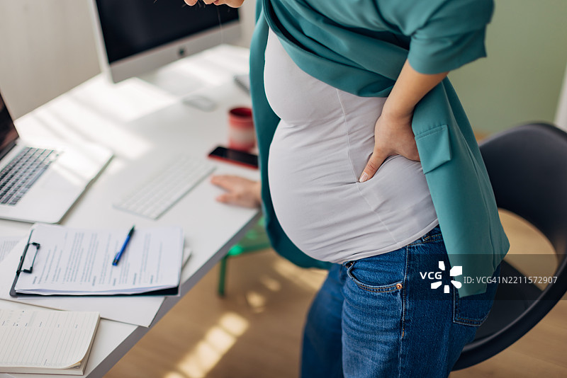 无法辨认的孕妇商务女性在工作中感到剧烈的背痛图片素材