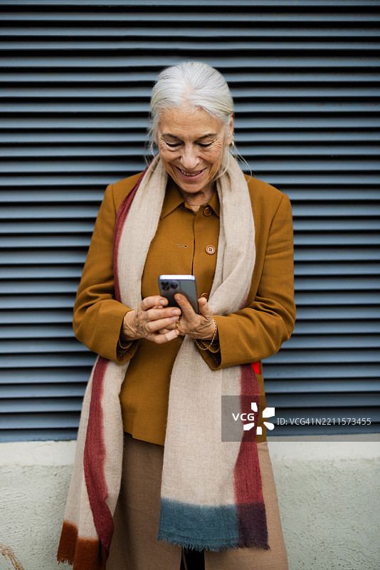 一位快乐的老年女性正在用智能手机发短信图片素材