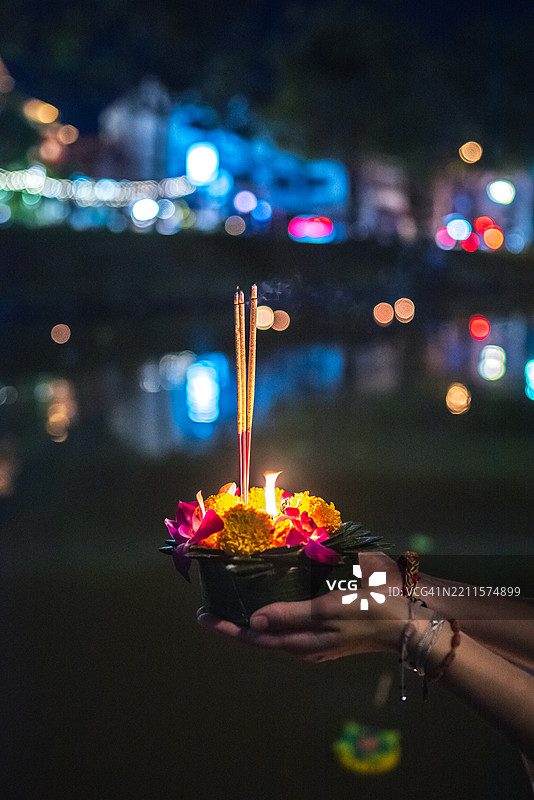 女人的手在泰国水灯节期间于河边捧着供品。图片素材