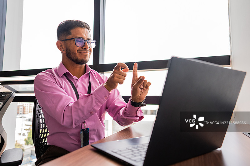 聋人商人在办公室通过笔记本电脑进行视频通话，使用手语交流图片素材