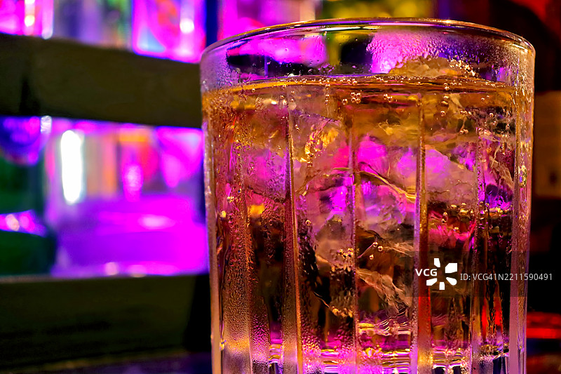 夜总会桌子上的威士忌玻璃杯，里面放着冰块。图片素材