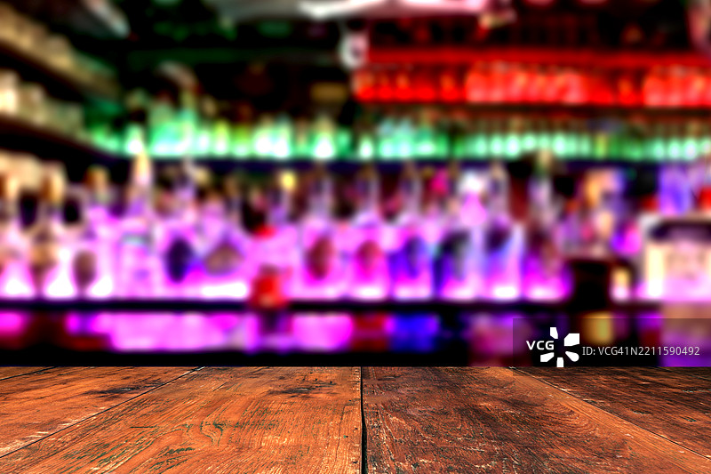 空荡荡的深色木桌，前景是餐厅或夜总会的模糊抽象散景背景。图片素材