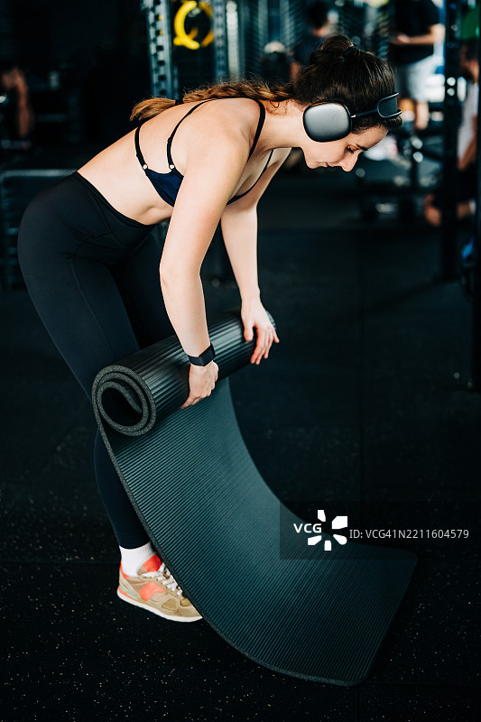 一位女性在折叠瑜伽垫。图片素材