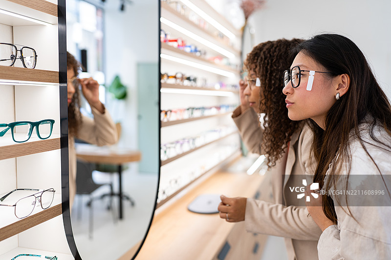 两位年轻女性在眼镜店挑选眼镜图片素材