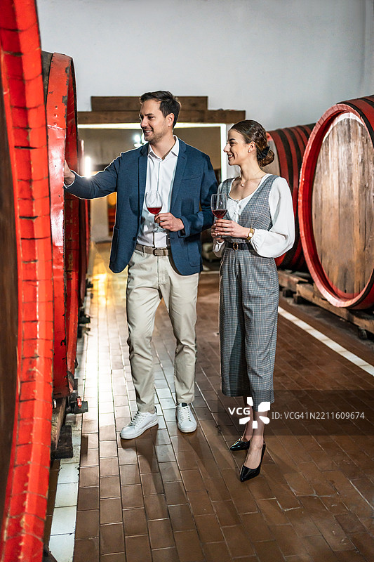 年轻男女在酒窖中品尝木桶里的葡萄酒图片素材