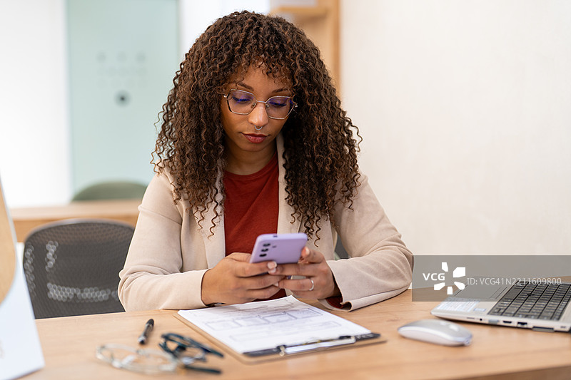 眼镜店的验光师在桌子上使用智能手机图片素材