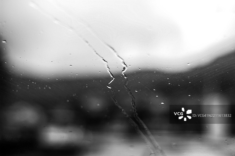 黑白色的汽车窗户上的雨滴，模糊的背景图片素材