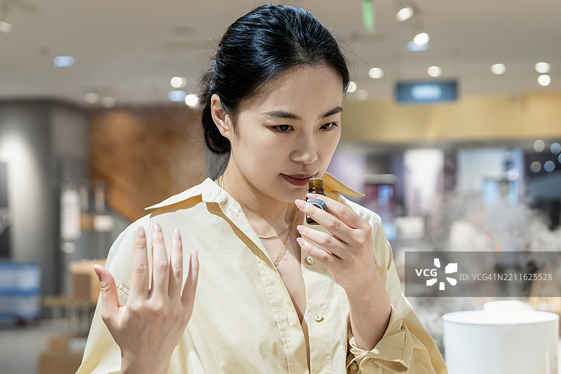 注重生活的家居必需品：一位中年亚洲女性在环保家居用品店购物，寻找有机天然家居香氛产品。图片素材