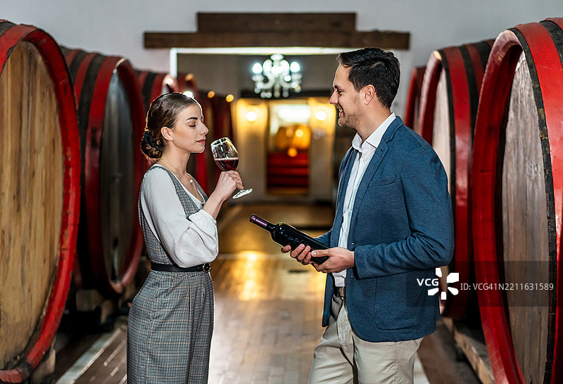 侍酒师在装有木桶的酒窖中品尝红酒图片素材