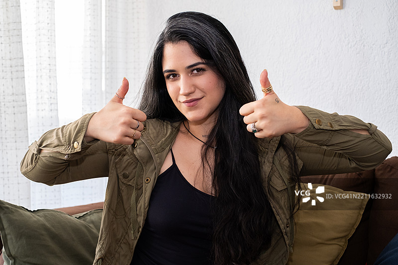 微笑的拉丁裔女性，面向镜头并竖起大拇指。图片素材