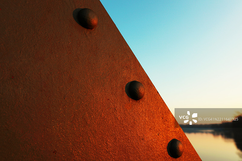 夕阳下的钢铁上有三个铆钉图片素材