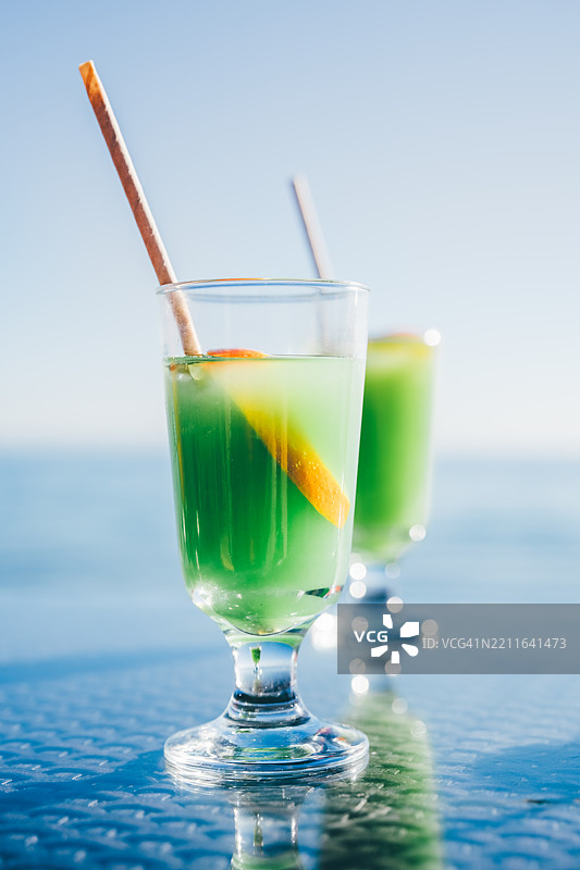 海滩上，明亮的鸡尾酒与海洋背景相映成趣。图片素材