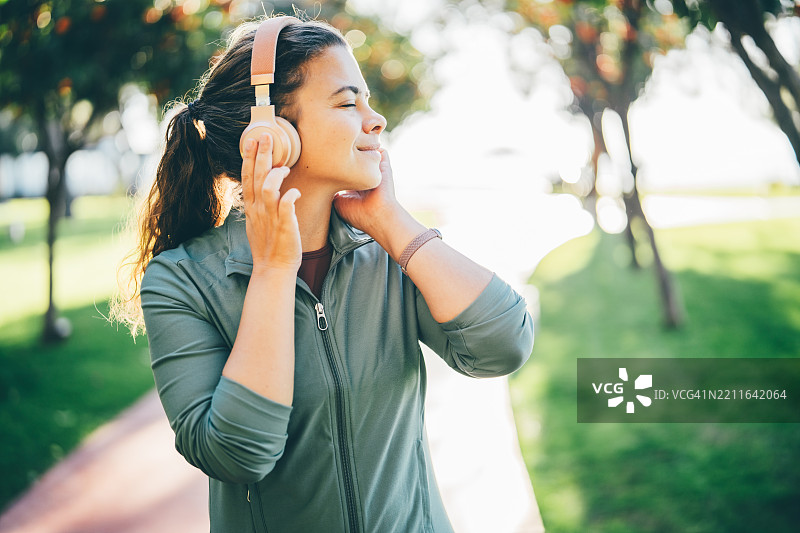 一位戴着耳机的女性在早晨的公园里跑步。图片素材