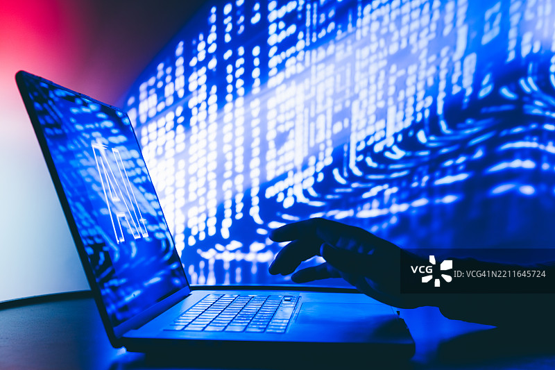 男子在霓虹灯下使用带有人工智能界面的笔记本电脑。图片素材