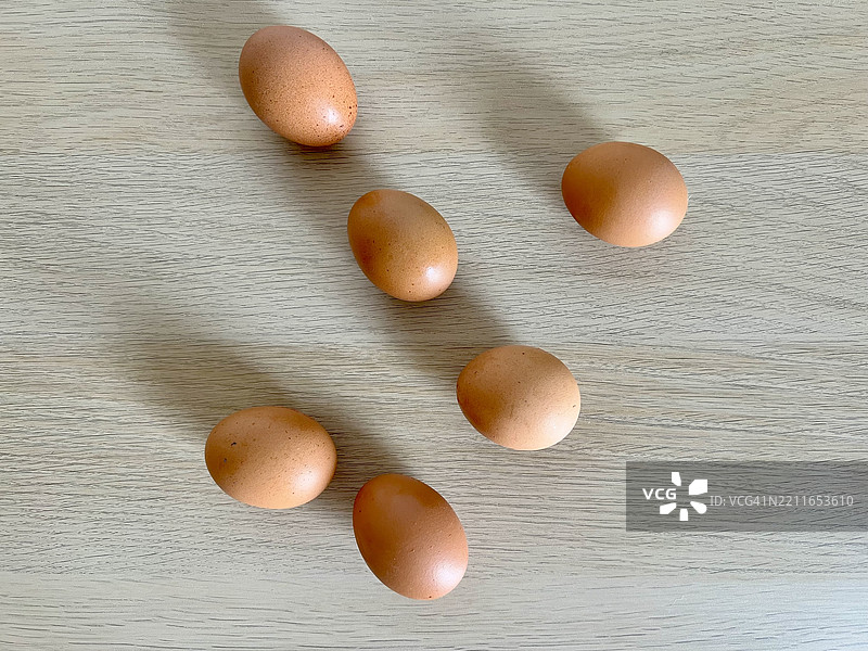 许多棕色鸡蛋散落在浅色木质表面上图片素材