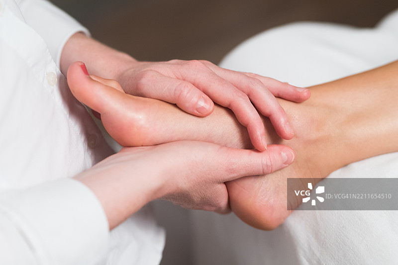 专业女性按摩师为女性足部进行反射疗法按摩图片素材