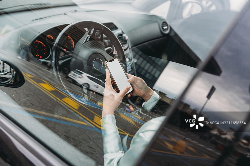 女商人在车内坐着使用带空白屏幕的智能手机图片素材