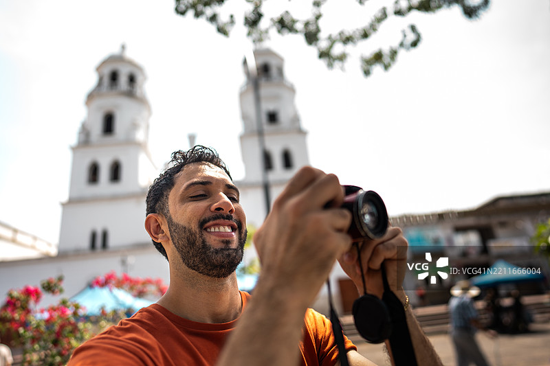 中年男子在哥伦比亚布卡拉曼加的历史区用数码相机拍照图片素材