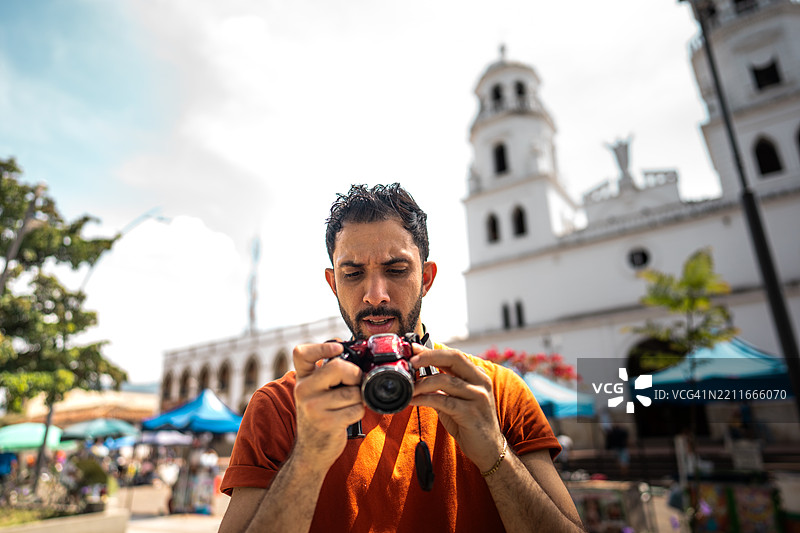中年男子在哥伦比亚布卡拉曼加的历史区用数码相机查看照片图片素材