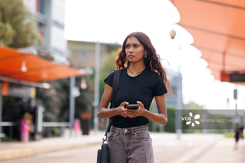年轻的澳大利亚土著女性在城市火车站等候图片素材