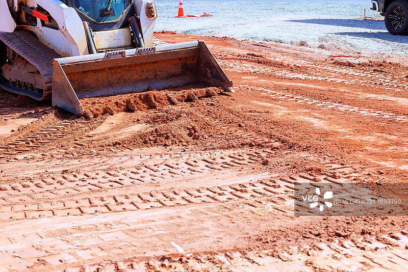 阳光明媚的区域，建筑工地上重型机械正在平整土壤图片素材