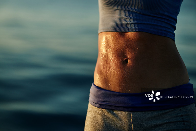 运动女性腹部的特写，满是汗水。图片素材