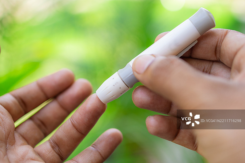 糖尿病：手部特写，使用刺血器进行血糖测试图片素材