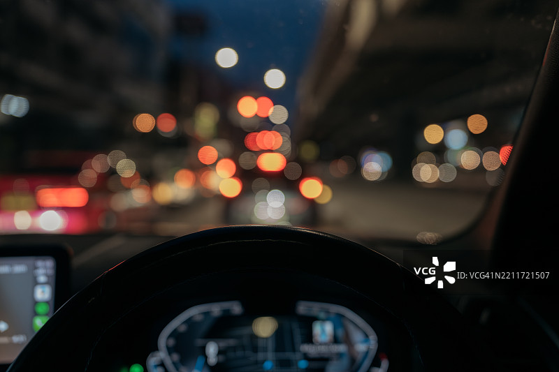车内仪表盘透视的夜间交通与城市灯光虚化效果图片素材