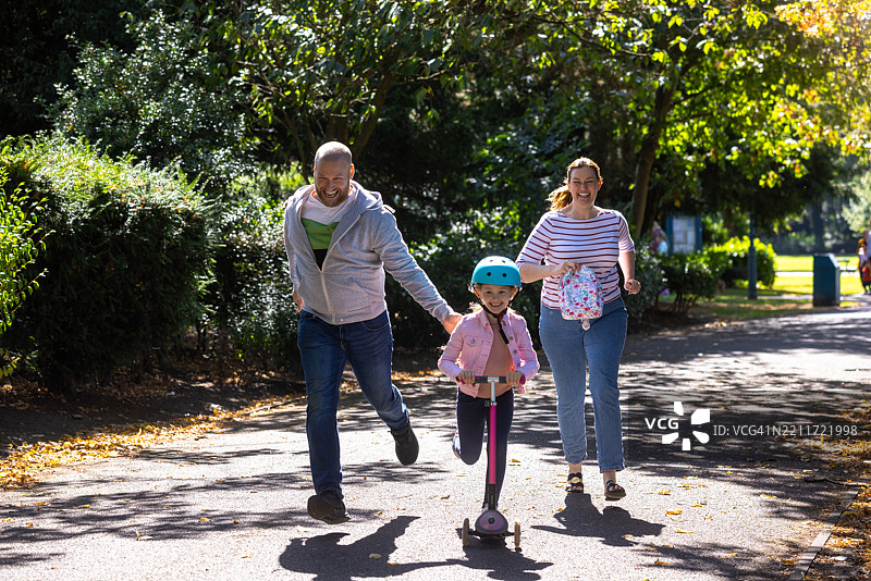父亲推着女儿骑滑板车图片素材