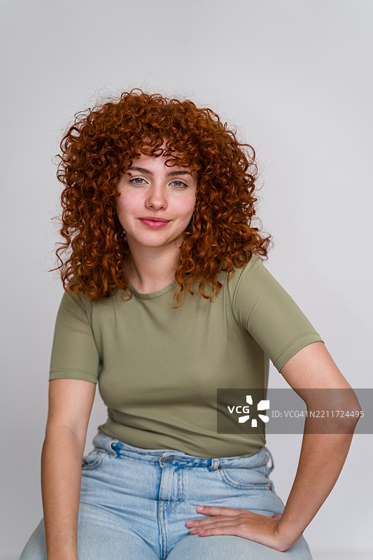 年轻女子，红色卷发，摆姿势并注视镜头图片素材