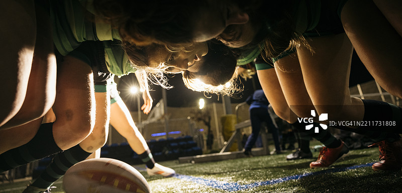女子橄榄球队在夜间训练中准备进行争球图片素材