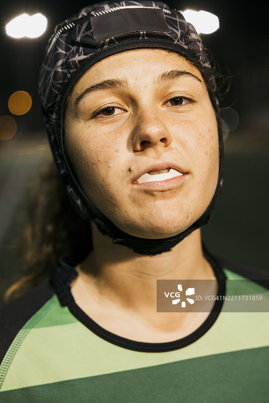 夜间穿戴保护头盔和护齿的女橄榄球运动员图片素材