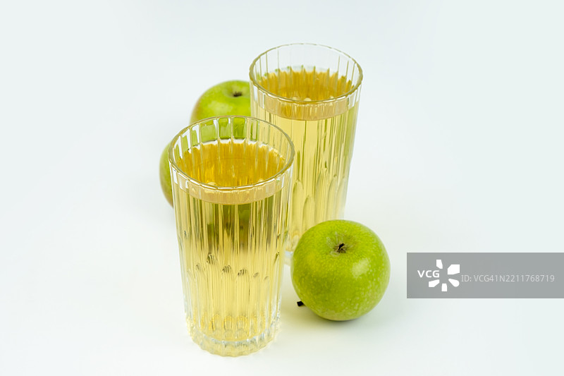 两杯苹果汁和绿色苹果。白色背景。图片素材