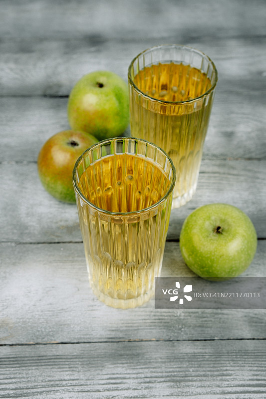 两杯苹果汁和绿色苹果。图片素材
