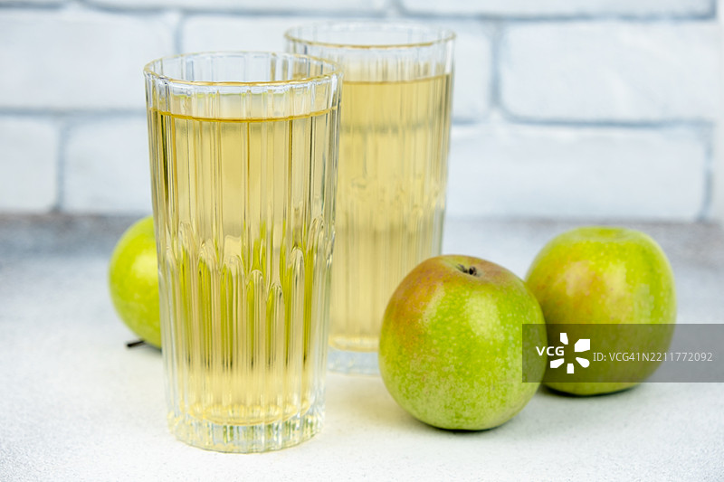 两杯苹果汁和绿色苹果。图片素材