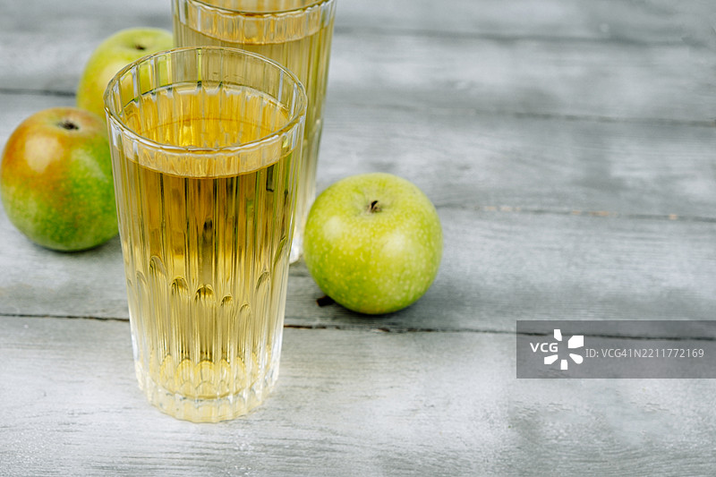 两杯苹果汁和绿色苹果。图片素材