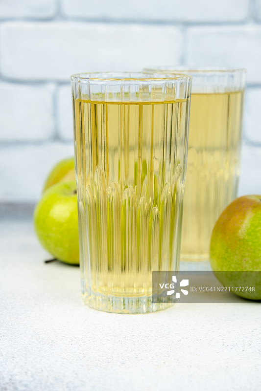 两杯苹果汁和绿色苹果。图片素材