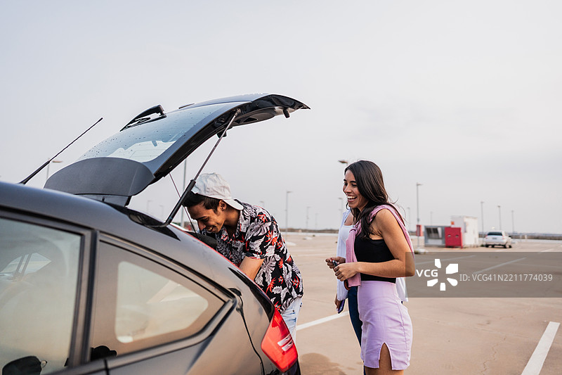 年轻朋友在机场停车场从汽车后备箱卸货或装货图片素材