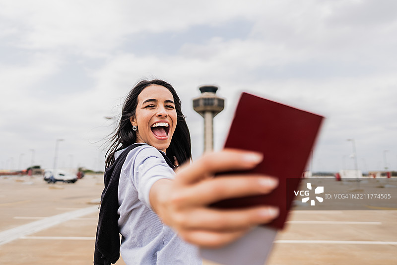 年轻女商人在机场停车场展示她的护照图片素材