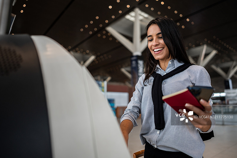 年轻女商人在机场使用自助值机机图片素材