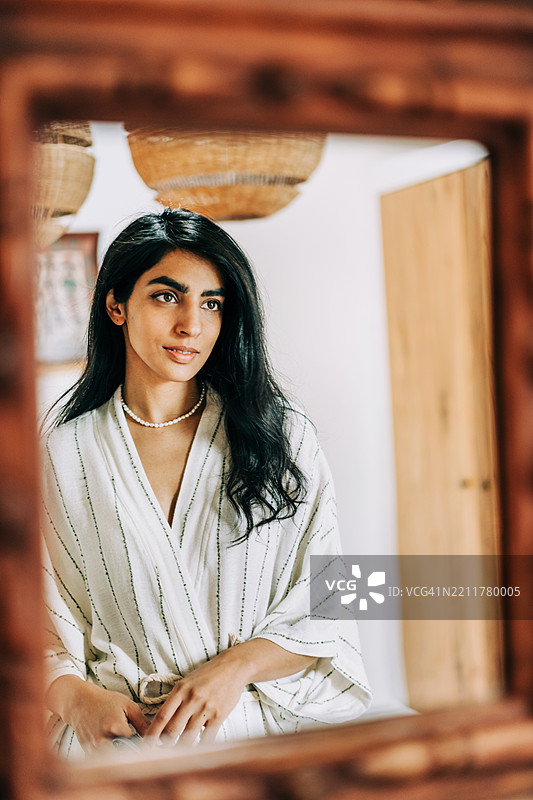 一位美丽的女性凝视着一面古老的镜子。图片素材