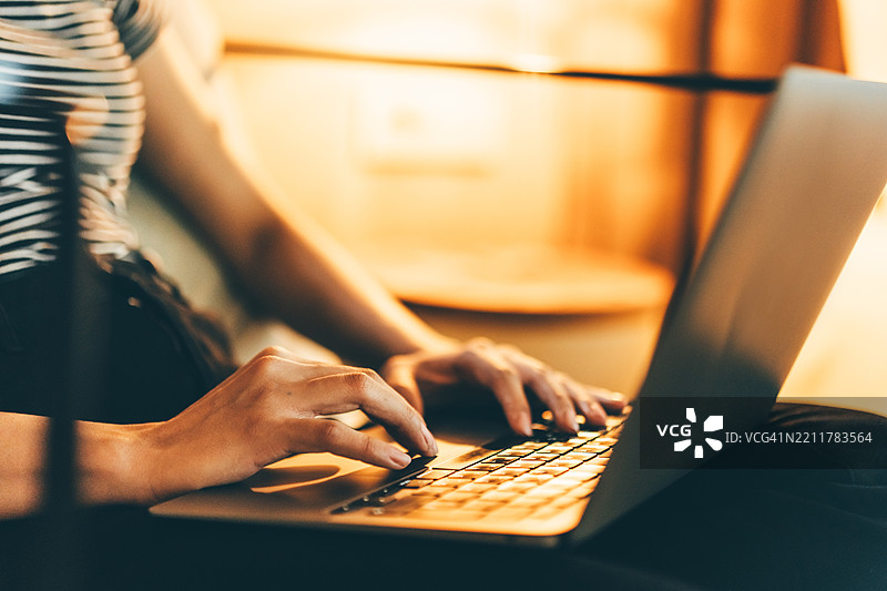 晚上，女人在家中使用笔记本电脑。图片素材