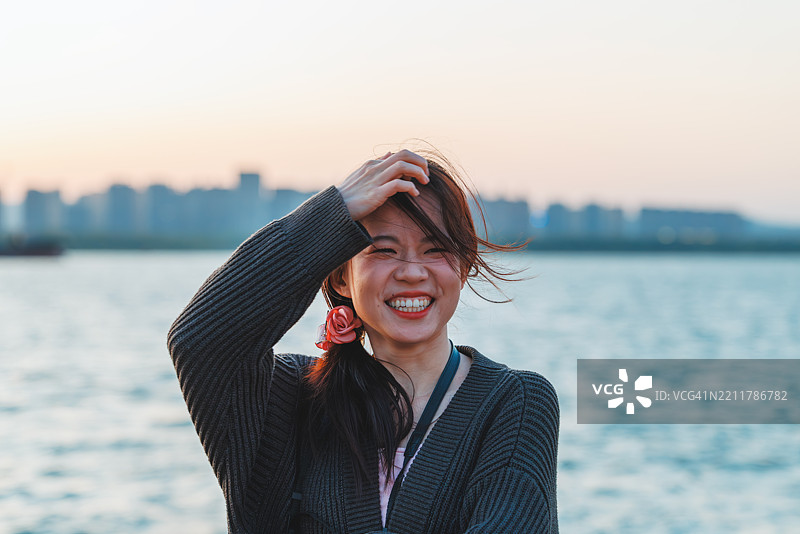 一位二十多岁的亚洲女性在日落时分户外微笑着，享受着爱情。图片素材