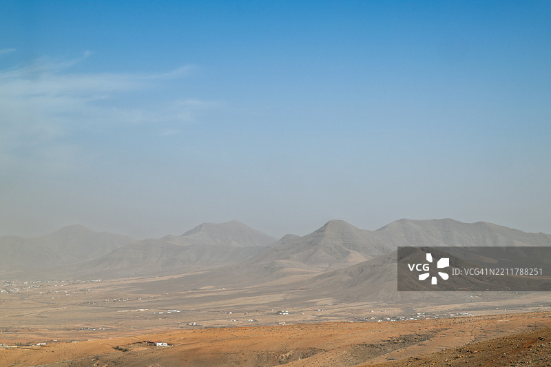 富埃特文图拉的风景，展现了干旱的平原和火山山脉，笼罩在沙尘天气下。图片素材